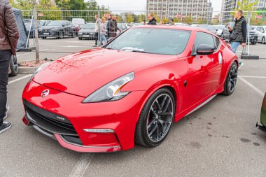 Beton bir zemine park etmiş kırmızı bir Nissan GT-R, muhtemelen bir otopark ya da garaj yolunda. Spor arabaların siyah çatısı, yan aynaları, jantları ve lastik markası Aerodinamik d Kyiv, Ukrayna 10-12-2024