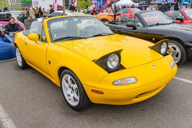 Ukrayna, Kyiv 'de 10-12-2024 sayılı bir etkinliğe park edilmiş, ön tamponunda patlak farlar ve hasar tespitleri olan klasik sarı bir spor araba.