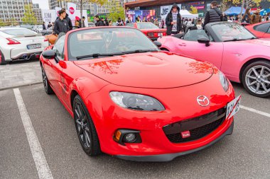 Kırmızı bir Mazda Miata açık hava etkinliğinde park etmiş, muhtemelen bir otomobil fuarı ya da sokak festivali, çeşitli renkli arabaların arka planında geçen sahne Ukrayna, Kyiv, 10-12-2024 üzerindedir.