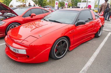 Kırmızı modifiye edilmiş spor bir araba, muhtemelen İngiliz NK 84 plakalı, farklı bir vücut kiti, büyük bir arka kanat spoiler, beş dilli siyah tekerlekler, ve aerodinamik şekil The Kyiv, Ukrayna 10-12-2024