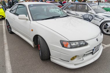 Beyaz, modifiye edilmiş bir spor araba yol kenarında ya da park yerinde park halindedir. Araç, daha büyük tampon girişleri, Sid Kyiv, Ukrayna 10-12-2024 gibi aerodinamik özelliklerinden dolayı agresif bir görünüme sahiptir.