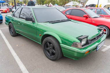 Halka açık bir caddeye park edilmiş yeşil, eski model bir spor araba. Geniş gövdeli bir seti, geniş alaşımlı tekerlekleri ve arka ayağında aerodinamik elementleri var. Kyiv, Ukrayna 10-12-2024