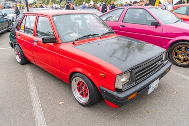 Klasik kırmızı ve siyah bir araba, muhtemelen yüksek performanslı bir model, açık hava etkinliğinde park edilmiş. Kaputu, özel boyası, krom tekerlekleri, dikiz aynası, vi Kyiv, Ukrayna 10-12-2024