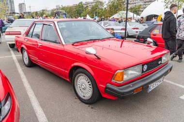 Muhtemelen 20. yüzyılın sonlarından ya da 21. yüzyılın başlarına ait olan kırmızı klasik bir araba potansiyel bir park alanına park edilmiştir. Renkli tamponları, Ukrayna, Kyiv, Ukrayna 10-12-2024