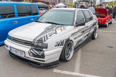 Vücut modifikasyonları ile kişiselleştirilmiş bir hatchback, şehir merkezine park edilmiş, beyaz ve renkli grafiklerin bir karışımı, muhtemelen sponsorları veya markaları temsil ediyor Diğer Kyiv, Ukrayna 10-12-2024