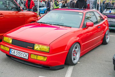 Bir etkinlikte asfalta park etmiş, parlak kırmızı renkli spor bir araba, parlak bir tasarım, büyük alaşımlı tekerlekler, aerodinamik gövde panelleri, spoiler ve pos Kyiv, Ukrayna 10-12-2024