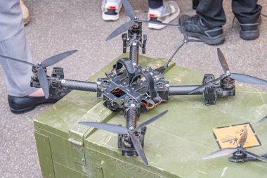 Bir kuadkopter drone yeşil bir depolama konteynırının üzerinde yatıyor, muhtemelen bir yol ya da kaldırımda. Gizli görüntü Kyiv, Ukrayna 10-12-2024 'ü detaylandıran İHA' ları yakalıyor.