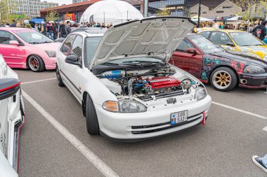 Birkaç modifiye arabanın yer aldığı bir otomobil fuarı veya sergisi, ön planda bir Japon aracına odaklanmış kalabalık Ukrayna, Kyiv, 10-12-2024 çıkışında gün ışığı altında araçlara hayran kalıyor.