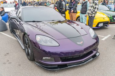 Açık hava otoparkında mor bir spor araba park halindedir, yakınındaki insanların olduğu araba parlak bir tasarıma, parlak bir tasarıma, alaşımlı tekerleklere sahiptir ve muhtemelen yüksek performanslı bir Th Kyiv, Ukrayna 10-12-2024 modelidir.