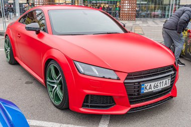 Kırmızı bir Audi R8 spor arabası, muhtemelen bir sokağa ya da otoparka park edilmiş, yarış veya aşırı sürüş için özel modifikasyonlar sergiliyor. Görüntü sıradan bir fotoğraf, t Kyiv, Ukrayna 10-12-2024