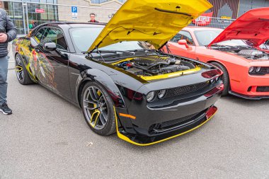 Görüntü, sarı aksanlı ve gelişmiş mekanik parçalı muhtemelen bir araba fuarında ya da sergide modifiye edilmiş siyah bir spor araba gösteriyor.