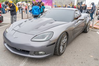 Bir şehir sokağına park etmiş parlak gri bir spor araba, muhtemelen bir araç vitrininde. Arabanın büyük alaşımlı tekerlekleri, hava girişleri ve görünür bir yayan yok. Kyiv, Ukrayna 10-12-2024