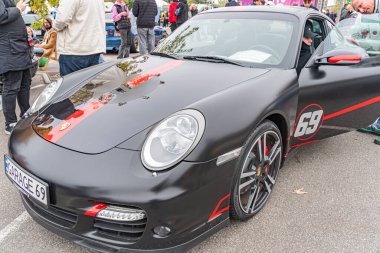 Görüntü belirgin tasarım özelliklerine sahip siyah ve kırmızı bir Porsche 918 Spyder 'ı halka açık bir etkinlikte veya sergide gösteriyor. Araba Kyiv, Ukrayna 10-12-2024 aktif süspansiyon sistemine sahip gibi görünüyor.