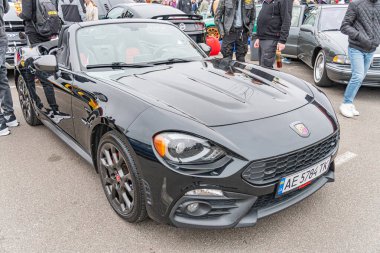 Ayırt edici tasarım unsurları ve rozetleri nedeniyle yüksek performanslı bir BMW modeli olan siyah bir spor araba, bir açık hava etkinliğinde park edilmiş, parlak görünümünü sergiliyor ve Kyiv, Ukrayna 10-12-2024