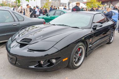 Kırmızı aksanlı siyah bir spor araba bir otomobil fuarında ya da sergide park halinde. Aracın parlak, düşük profilli bir tasarımı ve açılı far lambaları var. Arka plan Kyiv, Ukrayna 10-12-2024