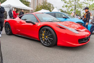 Kırmızı bir spor araba, muhtemelen bir Ferrari, halka açık bir yere park edilmiş, araba parlak kıvrımlara, geniş hava girişlerine, beş dilli sarı aksanlı alaşımlı tekerlere, ve sarı Kyiv, Ukrayna 10-12-2024