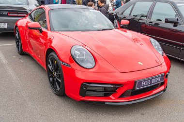 Ferrari Rent 'ten kiralanmış parlak kırmızı bir Porsche, yuvarlak farlar, hava girişleri ve Kyiv, Ukrayna 10-12-2024 gibi ayırt edici tasarım özelliklerini ön plana çıkaran bir şehir asfaltı üzerine açılıdır.