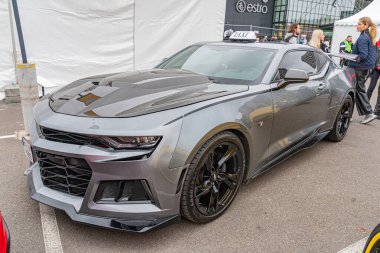 Gri bir Chevrolet Camaro, modifikasyonlar ve performans güncellemeleri içeren gösterişli bir tasarımı olan bir otomobil fuarında sergileniyor. Arabanın vücut kiti var, siyah çok dilli tekerlekleri Kyiv, Ukrayna 10-12-2024