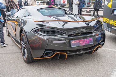 Siyah ya da koyu renkli, üstü açık, turuncu ve siyah renkli bir spor araba pistte park halinde. Araç aerodinamik tasarım elementi Kyiv, Ukrayna 10-12-2024