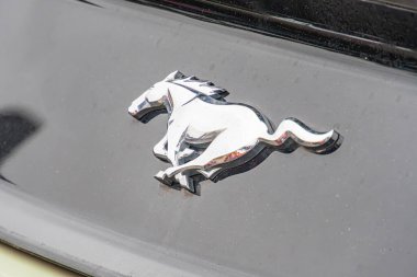 Görüntü, Ford Mustang logosunun siyah arka planda yakın plan görüntüsü, gücü ve hızı sembolize ediyor. Logo yükselen bir atı gösteriyor, yüksek performanslı araç Te Kyiv, Ukrayna 10-12-2024
