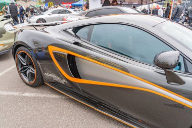 Pürüzsüz, aerodinamik tasarımı olan yüksek performanslı bir spor araba asfalt zemine park edilmiştir. Aracın yan hava girişleri, arka spoiler, çok dilli tekerlekler, bir Kyiv, Ukrayna 10-12-2024