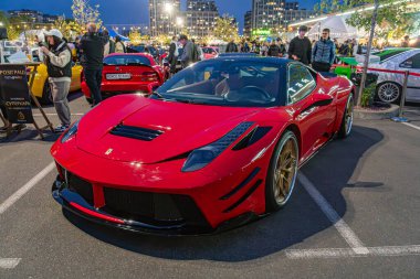 Kırmızı bir Ferrari spor arabası arka planda yürüyen insanların bulanık figürleriyle bir otomobil fuarında veya etkinlikte belirgin bir şekilde sergileniyor. Kapalı mekan ayarları Ukrayna, Kyiv, 10-12-2024
