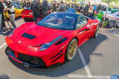 Aerodinamik özelliklere sahip canlı kırmızı bir spor araba bir gösteri ya da lüks arabaların toplanması halinde park edilmiş durumda. İnsanlar bu tür araçların sergilendiği bir etkinlik öneriyor. Kyiv, Ukrayna 10-12-2024