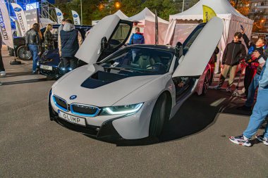 Açık hava etkinliklerinde BMW i8 spor araba sergileniyor. Beyaz ve siyah araçların kapıları açık. Bu da Kyiv, Ukrayna 10-12-2024