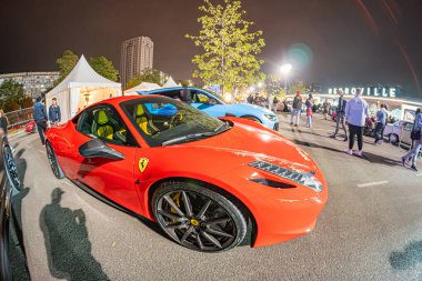 Görüntü, halka açık bir toplantıda muhtemelen lüks veya süper araba markasından üstü açık kırmızı bir spor araba gösteriyor. Sahne loş bir şekilde aydınlatılmış ve fotoğraf kaptanı Kyiv, Ukrayna 10-12-2024