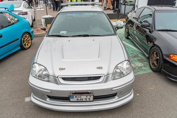Eski bir model, iki kapılı gri bir coupe araba. Açılır tavan ve piyasa modifikasyonları hava kepçesi, halka açık bir alana park edilmiş çıkartmalar. Plakasında C61-489 Fotoğrafı Kyiv, Ukrayna 10-12-2024 yazıyor.