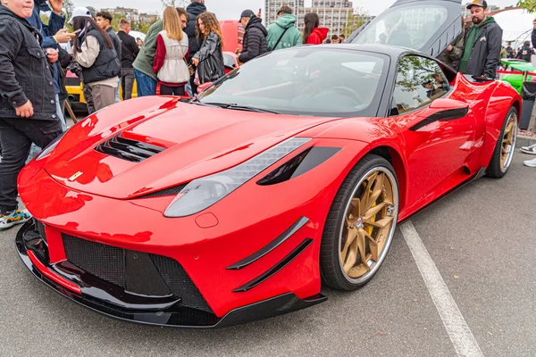 Canlı kırmızı bir spor araba muhtemelen Aston Martin, Ferrari ya da Lamborghini bir şehir caddesinde bir toplantıda park halindedir. Ayarlar iyi hava ve sıradan atmos Kyiv, Ukrayna 10-12-2024 'ü gösteriyor.