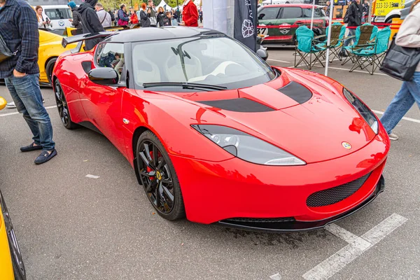 Gösterişli martı kanatlı kapıları olan üstü açık kırmızı bir spor araba, halka açık bir şehir ortamında park edilmiş, ön tarafında yaya aktiviteleri ve diğer Kyiv, Ukrayna 10-12-2024