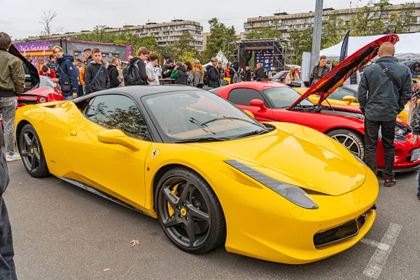 Canlı sarı bir spor araba, muhtemelen Lamborghini Gallardo, asfalt bir zeminde köşegen olarak park edilmiştir. Bir halk etkinliğinde arka planda insanlar vardır veya Ukrayna, Kyiv, 10-12-2024 'e erişimi vardır.