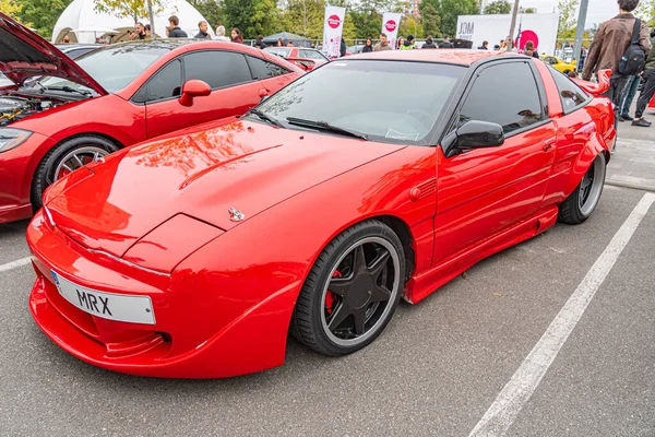 Kırmızı modifiye edilmiş spor bir araba, muhtemelen İngiliz NK 84 plakalı, farklı bir vücut kiti, büyük bir arka kanat spoiler, beş dilli siyah tekerlekler, ve aerodinamik şekil The Kyiv, Ukrayna 10-12-2024