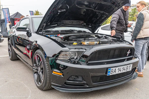 Açık kapüşonlu siyah bir Ford Mustang GT, muhtemelen bir araba yarışmasında, 50L V8 Ti-VCT motorunu sergiliyor. Kapalı alanda çekilmiş gizli bir fotoğraf ya da bulutlu bir günde Kyiv, Ukrayna, 10-12-2024