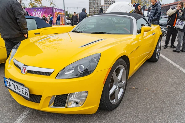 Belirgin bir açıyla yerleştirilmiş, parlak sarı bir spor araba, özel stili ve plakası GTE 016 FEB, bu resimde gösteriliyor. Arka plan figürleri Kyiv, Ukrayna 10-12-2024