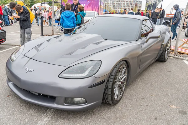 Bir şehir sokağına park etmiş parlak gri bir spor araba, muhtemelen bir araç vitrininde. Arabanın büyük alaşımlı tekerlekleri, hava girişleri ve görünür bir yayan yok. Kyiv, Ukrayna 10-12-2024