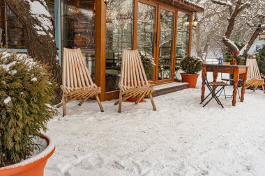 Kyiv 'deki VDNH sergi merkezinde kış şenlikleri ahşap masa ve sandalyeler, doğal ışıklandırma, sönük kahverengiler ve grilikler, açık hava oturma alanı Kyiv, Ukrayna - 15 Şubat 2025