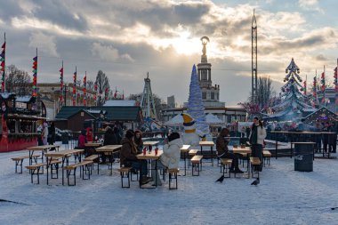 VDNH sergi merkezinde kış festivali, Kyiv Central kar kaplı açık alan tahtadan masalar ve yemek masaları, şenlikli süslemeler, bayraklar, hafif Kyiv, Ukrayna - 15 Şubat 2025