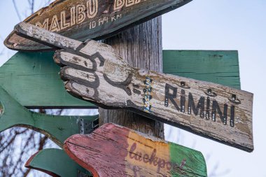 Kyiv, Ukrayna 'daki bir Kyiv, Ukrayna' dan gelen hafif kaynaklı, yıpranmış ve kırsal görünümlü, Malibu Sahili ve Rimini 'yi işaret eden yön işaretli aşınmış ahşap levha.