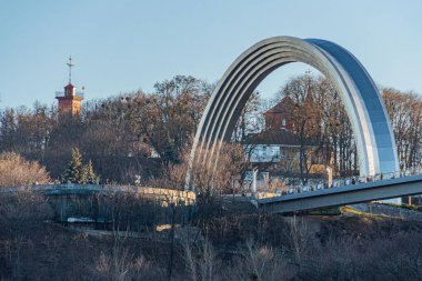 Kiev Gri metalik yapısı, dinamik kavisleri ve yemyeşil ağaçlar üzerindeki eğimli tasarımla modern köprü Kyiv, Ukrayna - 19 Ocak 2025