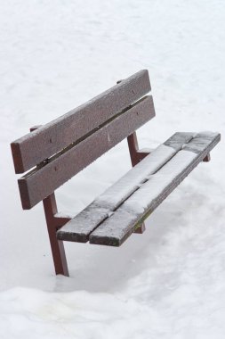 Huzurlu bir kış sahnesi. Huzurlu bir halk parkında kar birikintisi olan boş bir ahşap bank. Sakin ve soğuk havayı çağrıştırıyor..