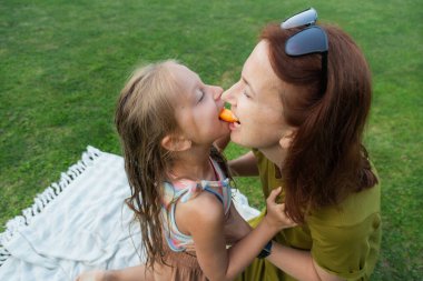 Bir anne ve kızı canlı yeşil bir parkta neşeli bir öğleden sonranın tadını çıkarıyorlar. Sıcak güneşin altında neşeli anılar yaratarak renkli bir oyuncakla gülüp meşgul oluyorlar..