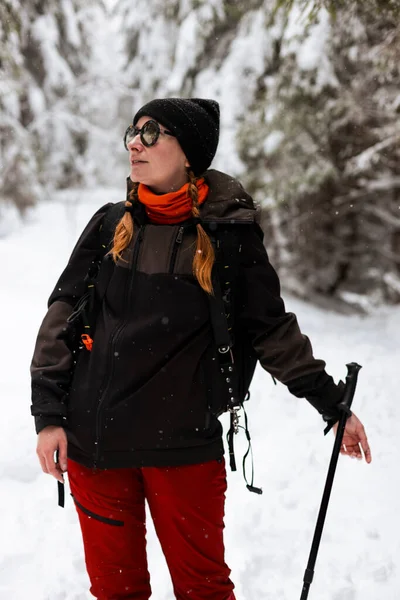 Beyazlarla kaplı uzun ağaçların arasında neşeli bir yürüyüşçü kışın harikalar diyarında şenlenir. Canlı kırmızı pantolonlar ve serin elbiseler ile serin macerayı kucaklar..