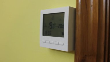 right side view of a heating thermostat in a yellow wall