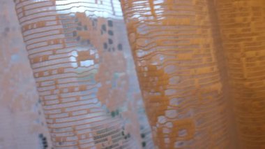 Perdelerin arkasında, yoldan bir araba geçiyor.