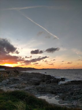Deniz üzerinde ve bulutların altında gün batımı renkleri
