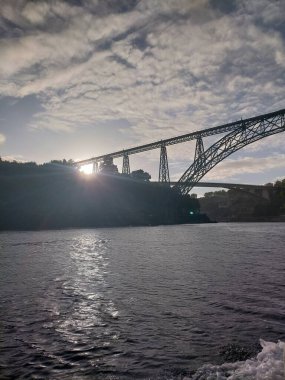 Portekiz 'in Porto şehrinde gün batımı, Douro nehrinde köprüler, bulutlar ve tarihi binalarla.