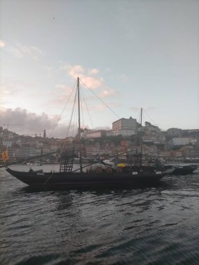 Portekiz 'in Porto şehrinde gün batımı, Douro nehrinde köprüler, bulutlar ve tarihi binalarla.