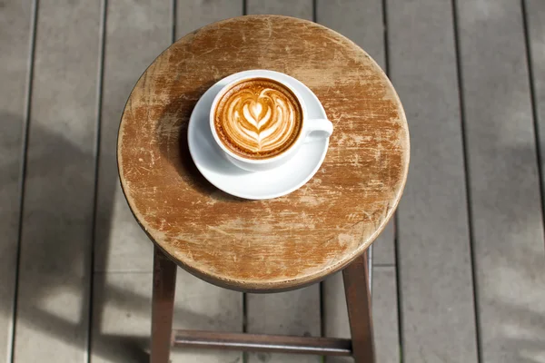 Caneca de latte quente, saboroso latte, um copo de garrafa com uma flor, um fundo cinza , — Fotografia de Stock